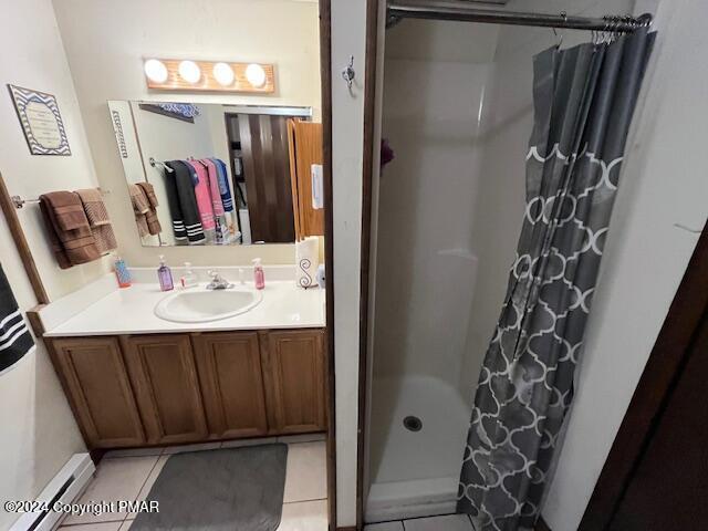 full bath featuring a baseboard heating unit, a shower stall, vanity, and tile patterned floors