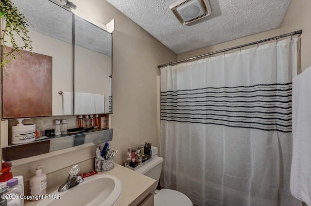 full bathroom featuring visible vents, toilet, a textured ceiling, and vanity