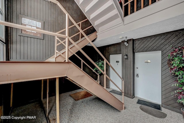 stairs with wooden walls and carpet floors