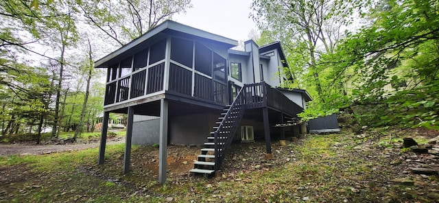 rear view of property featuring a sunroom, stairway, and a wooden deck