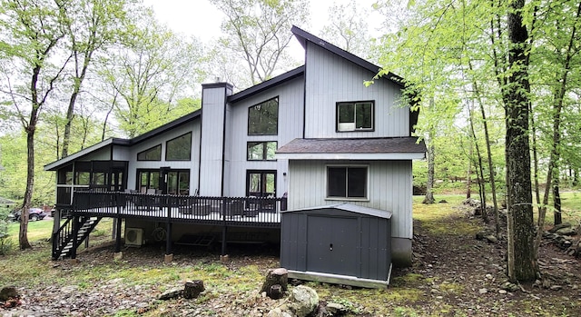 rear view of house with a storage unit, a deck, stairs, an outbuilding, and a chimney