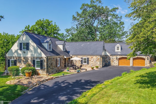 2711 Main St, Bethlehem, PA 18017 - cape cod home featuring stone siding, a garage, asphalt driveway, and a front lawn