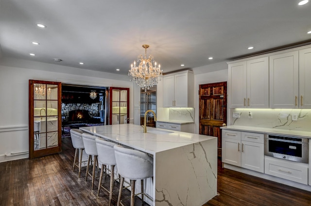 24 Summit Ave, Pocono Summit, PA 18346 - kitchen featuring oven, light stone countertops, a sink, dark wood-style floors, and a notable chandelier