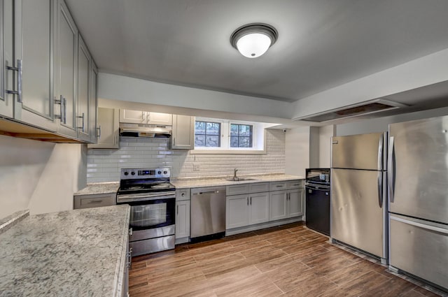 24 Summit Ave, Pocono Summit, PA 18346 - kitchen featuring tasteful backsplash, appliances with stainless steel finishes, under cabinet range hood, a sink, and gray cabinetry