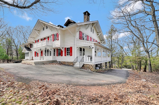 24 Summit Ave, Pocono Summit, PA 18346 - view of property exterior with a balcony, aphalt driveway, a chimney, board and batten siding, and covered porch