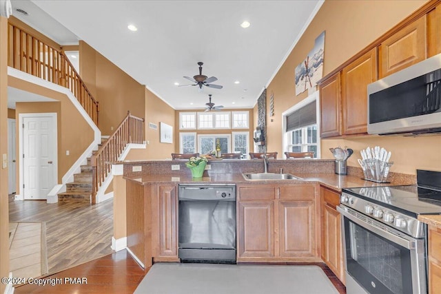 kitchen with a sink, wood finished floors, recessed lighting, stainless steel appliances, and a peninsula