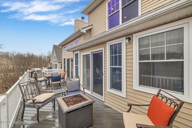 deck featuring outdoor dining space and a fire pit