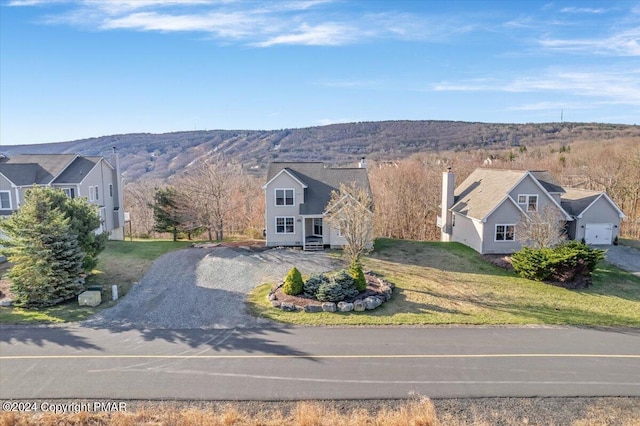 view of front of home with aphalt driveway, a mountain view, and a front yard