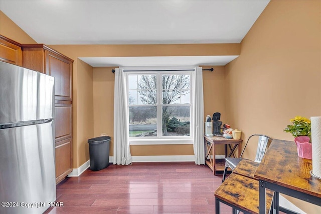 interior space featuring baseboards, dark wood finished floors, brown cabinetry, and freestanding refrigerator