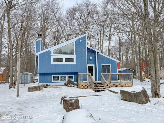 view of front of home with a chimney, a storage unit, a deck, and an outdoor structure