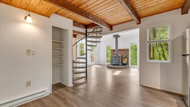 5015 Woodbridge Dr E, Bushkill, PA 18324 - unfurnished living room featuring a baseboard radiator, wooden ceiling with exposed beams, stairway, a wood stove, and wood finished floors