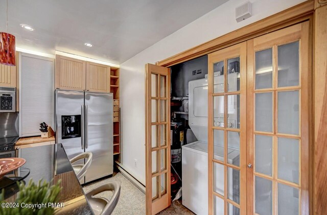 kitchen featuring visible vents, carpet, stainless steel appliances, stacked washing maching and dryer, and recessed lighting