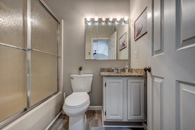 bathroom with toilet, vanity, shower / bath combination with glass door, and wood finished floors