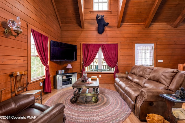 living area with lofted ceiling with beams, light wood-type flooring, wooden ceiling, and a healthy amount of sunlight