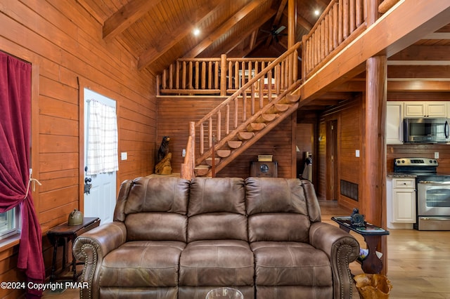 living room featuring high vaulted ceiling, wooden walls, wood ceiling, light wood finished floors, and beamed ceiling