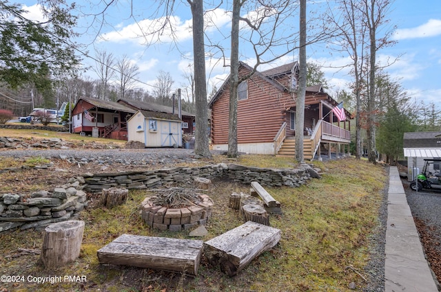 exterior space featuring stairway, an outdoor structure, a fire pit, and a shed