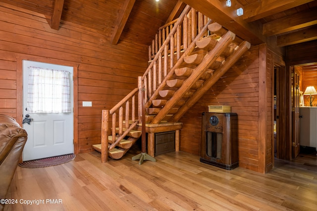 entryway featuring wood ceiling, light wood-style flooring, wooden walls, and lofted ceiling with beams