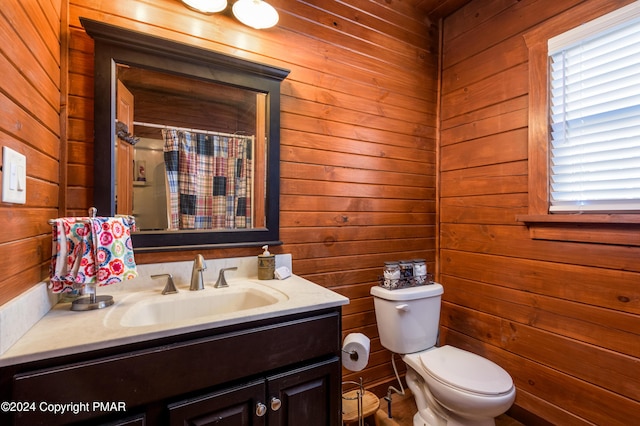 full bath featuring toilet, a shower with curtain, wooden walls, and vanity