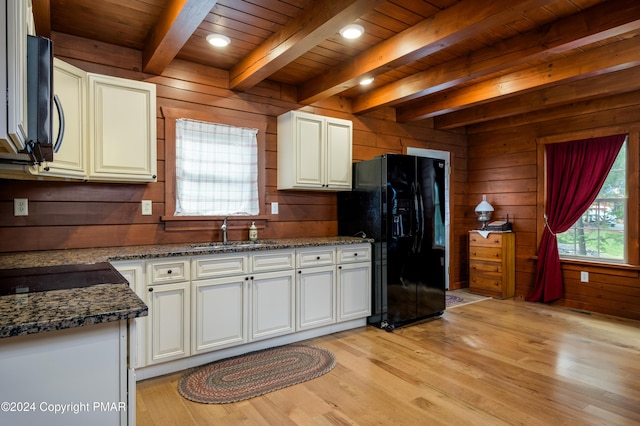 kitchen with white cabinets, a sink, wooden walls, light wood-type flooring, and black appliances