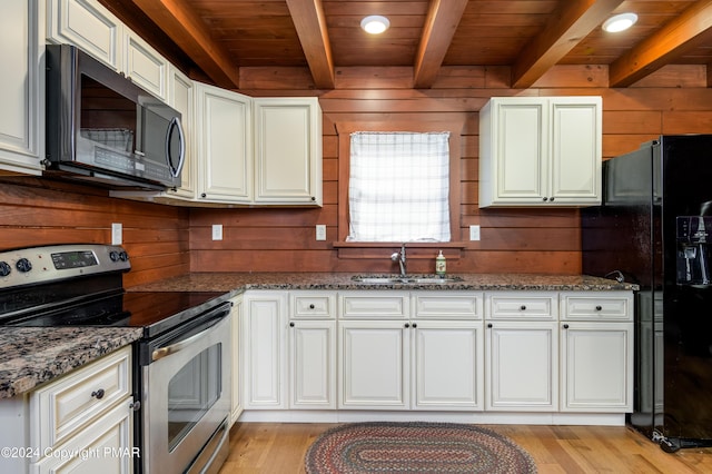 kitchen featuring wood walls, stainless steel electric range, a sink, and black fridge with ice dispenser