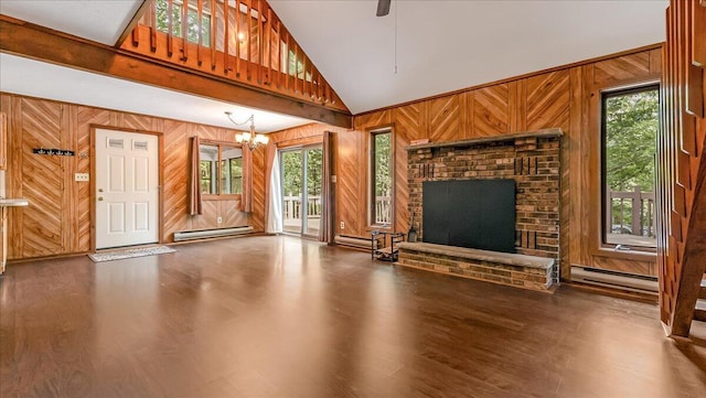 5913 NE Decker Rd NE, Bushkill, PA 18324 - unfurnished living room with wood walls, a baseboard heating unit, wood finished floors, high vaulted ceiling, and a chandelier