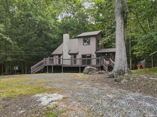 5913 NE Decker Rd NE, Bushkill, PA 18324 - rear view of house featuring a chimney, a wooden deck, a sunroom, stairway, and a shingled roof