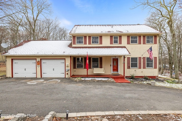 view of front of property with a garage, covered porch, driveway, and a shingled roof