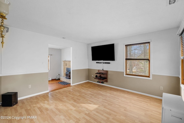 unfurnished living room featuring a brick fireplace, baseboards, and wood finished floors