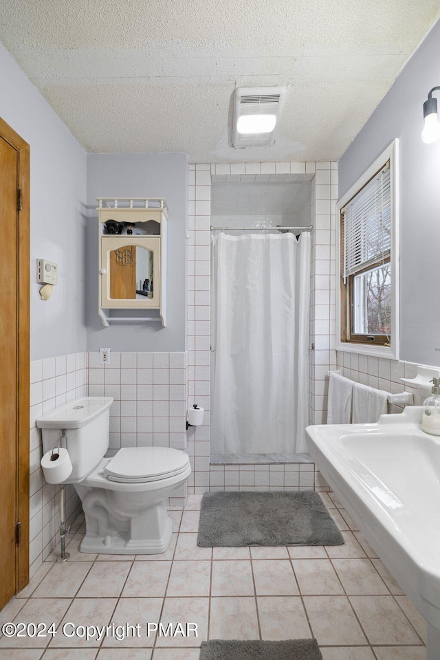 full bath featuring a textured ceiling, toilet, tile walls, and tile patterned floors