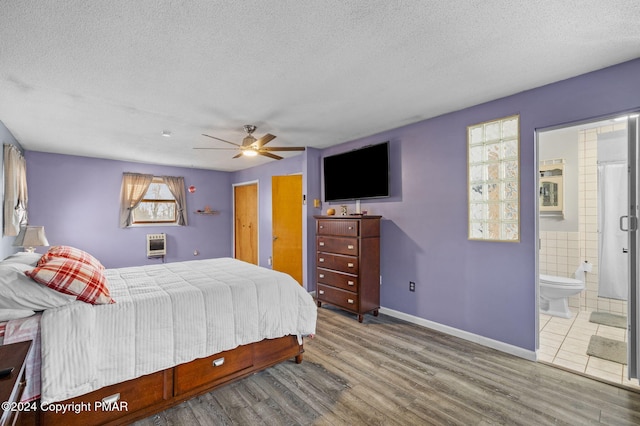 bedroom with a textured ceiling, baseboards, wood finished floors, and ensuite bathroom