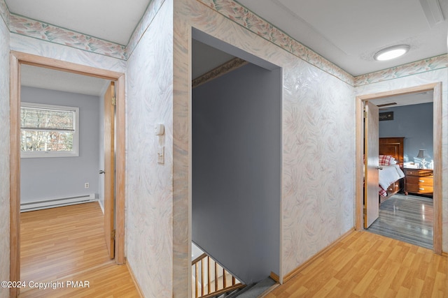 hall with wallpapered walls, baseboards, baseboard heating, and wood finished floors