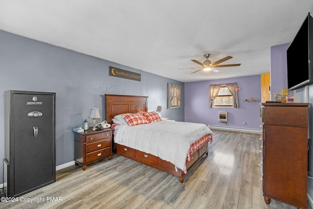 bedroom featuring ceiling fan, wood finished floors, baseboards, baseboard heating, and heating unit