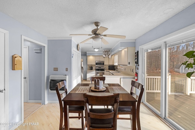 dining area with a textured ceiling, light wood-type flooring, a ceiling fan, and heating unit