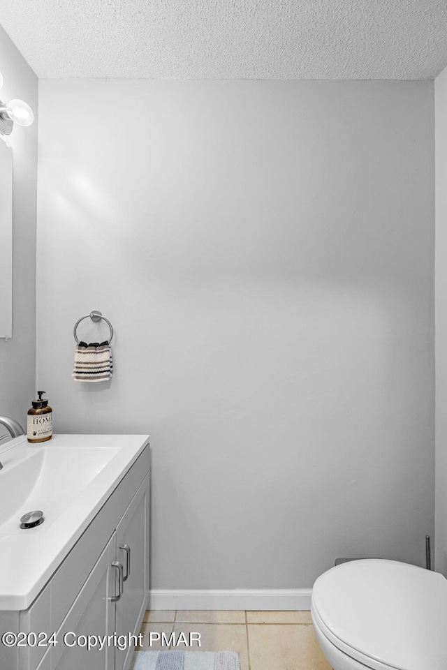 half bath featuring a textured ceiling, tile patterned flooring, vanity, and baseboards