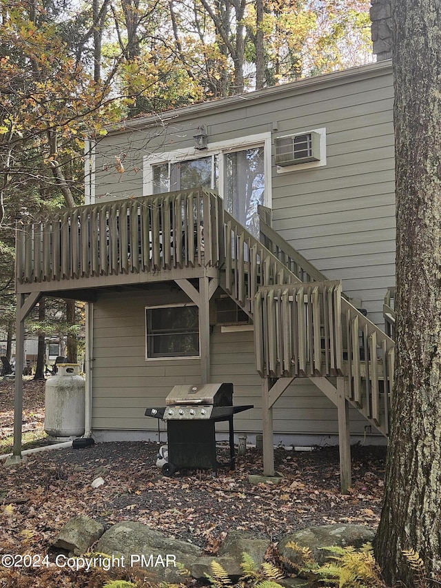 rear view of house with stairs, an AC wall unit, and a wooden deck