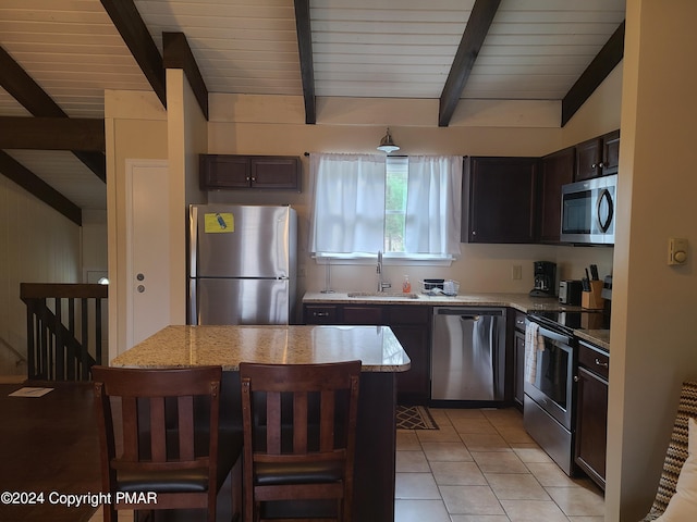 kitchen featuring light tile patterned floors, a kitchen island, a sink, appliances with stainless steel finishes, and light stone countertops