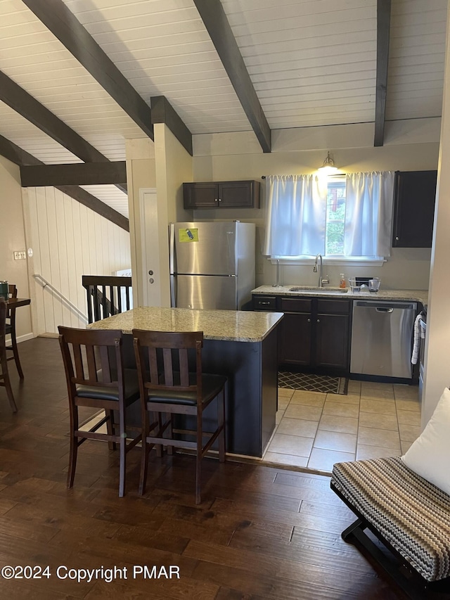 kitchen with a breakfast bar, stainless steel appliances, a sink, a kitchen island, and light wood-type flooring