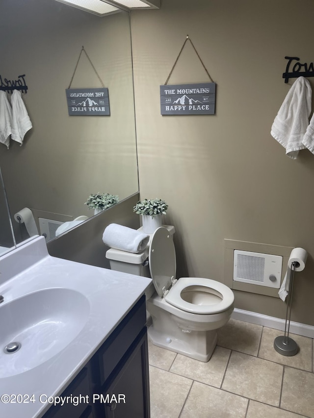 half bathroom featuring toilet, baseboards, vanity, and tile patterned floors