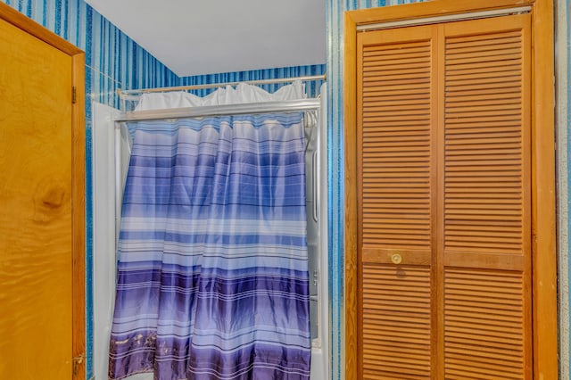 full bathroom with a closet, shower / bath combo with shower curtain, and wallpapered walls