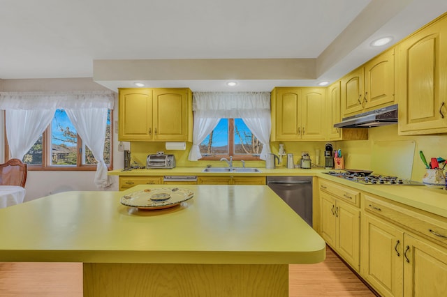 kitchen with under cabinet range hood, light countertops, stainless steel dishwasher, gas cooktop, and a sink