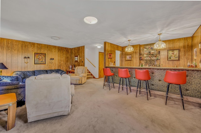 living room featuring stairway, wood walls, bar area, and carpet