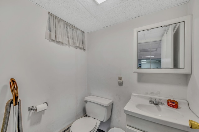 half bath featuring vanity, toilet, and a paneled ceiling