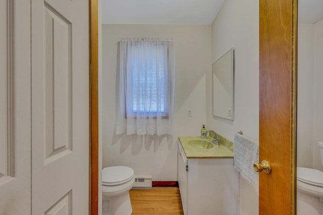 bathroom featuring vanity, toilet, a baseboard heating unit, and wood finished floors