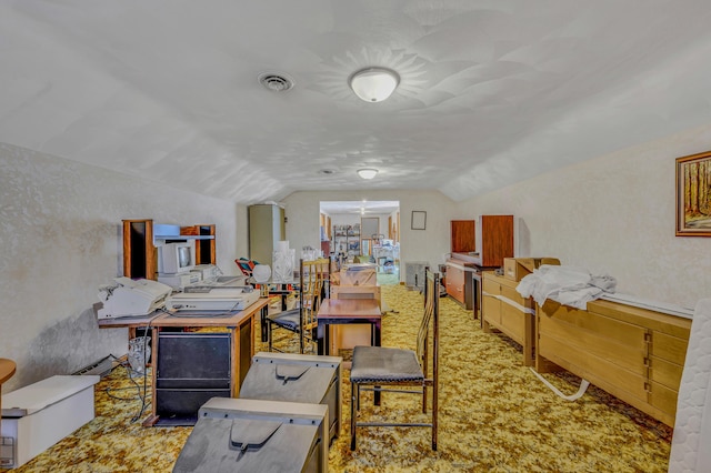 carpeted home office featuring visible vents and vaulted ceiling