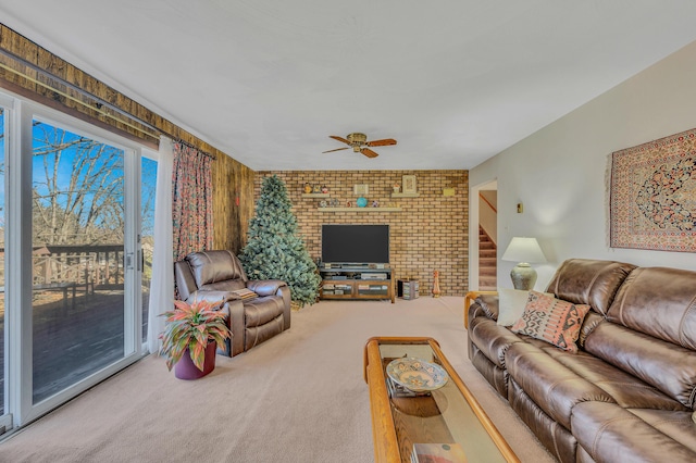 living room featuring stairway, carpet floors, brick wall, and a ceiling fan