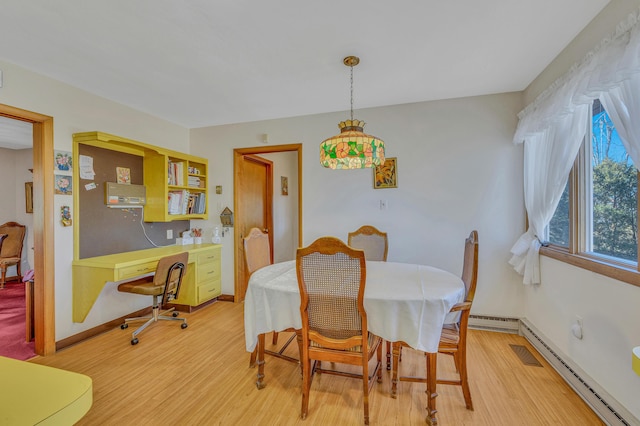 dining room featuring light wood-type flooring, a baseboard radiator, and baseboards