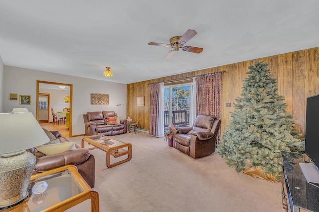 carpeted living area with wooden walls and ceiling fan