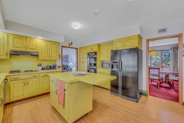 kitchen with under cabinet range hood, visible vents, black appliances, and light countertops