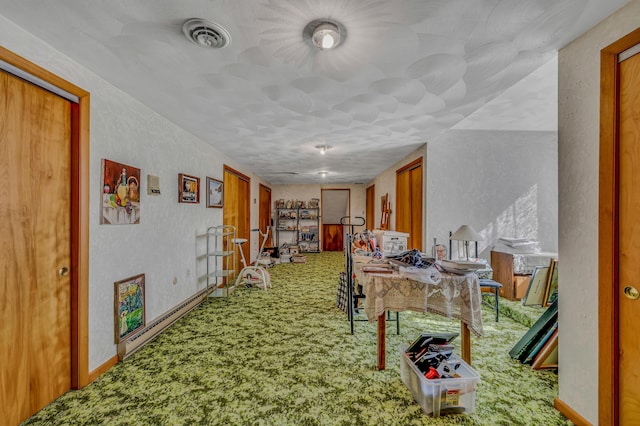 hall featuring visible vents, baseboards, carpet, a textured wall, and a baseboard radiator