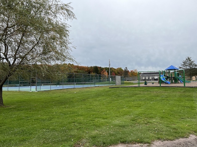 exterior space with playground community, a yard, a tennis court, and fence